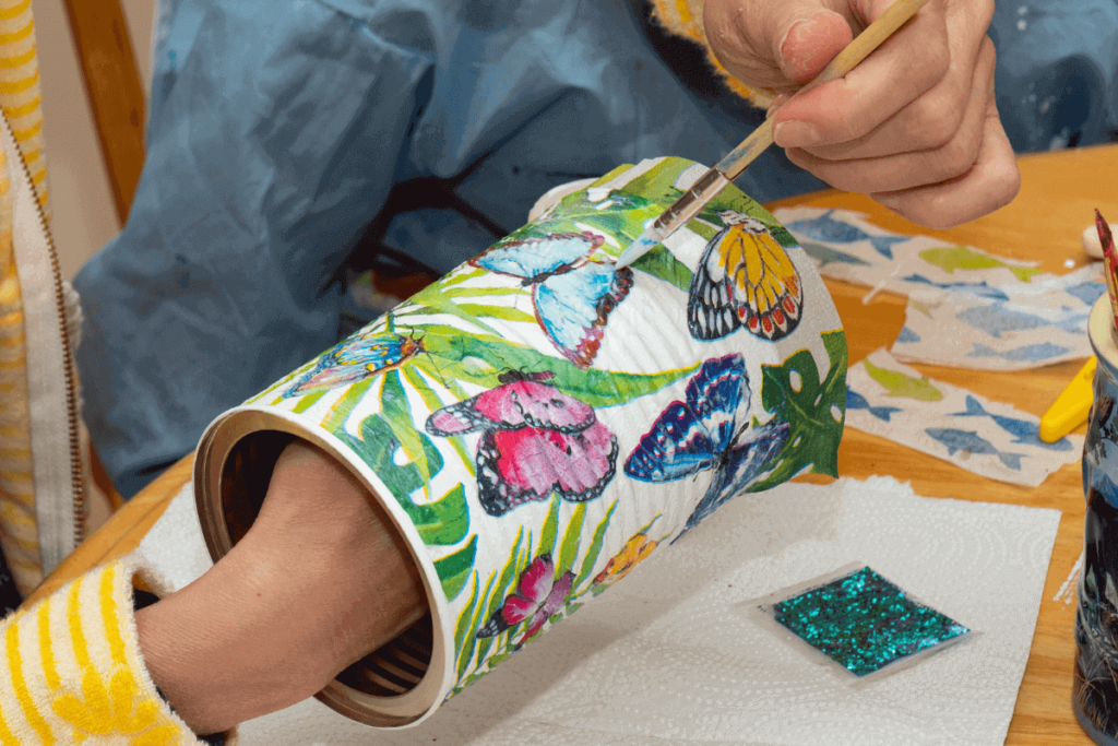 Mulher pintando latas de alumínio para suporte de utensílios