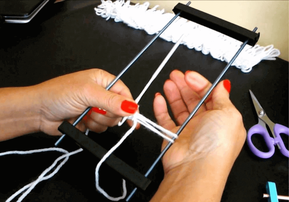 Imagem mostrando mãos femininos iniciando um trabalho com crochê de grampo.