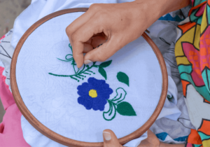 Imagem mostrando mãos de um artesão fazendo um bordado.